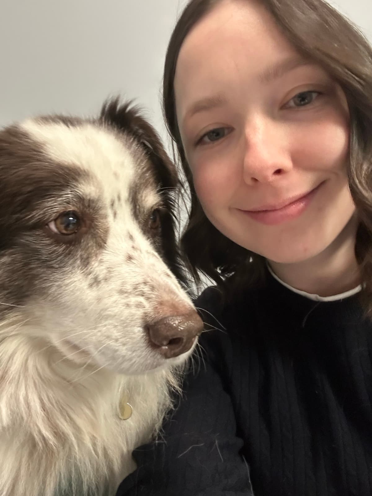 Liandra smiling in a close-up selfie beside a brown and white dog